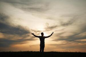 Silhouette of a man ,that is ,in the field at sunset time. Dramatic sky photo