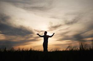 Silhouette, of a man that is in the field at sunset time. Dramatic sky photo