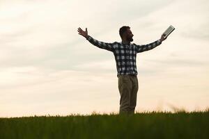 Enjoying freedom, with hands up. Handsome young man is on agricultural field photo