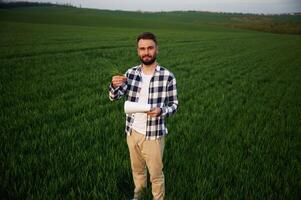 Front ,view. Standing and holding notepad with document. Handsome young man is on agricultural field photo