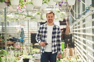 Positive ,florist man is working in garden center. Successful employee is in a bright greenhouse photo