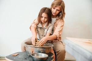 Making the pot out of clay.. Mother with little girl doing pottery at home photo