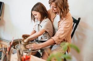 Having fun by making the ,ceramic pot,. Mother with little girl is in the workshop photo