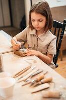 Little girl is learning how to do pottery in the workshop photo