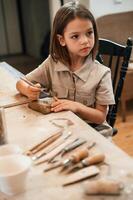 Different tools on the table. Little girl is learning how to do pottery in the workshop photo