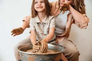 Making the pot out of clay., Mother with little girl doing pottery at home photo
