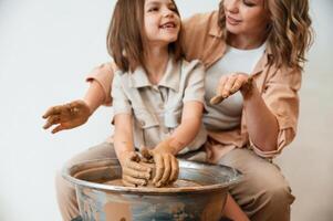 Making the pot out of clay,. Mother with little girl doing pottery at home photo