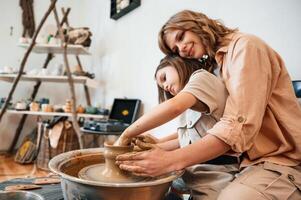 Having, fun ,by making the ceramic pot. Mother with little girl is in the workshop photo