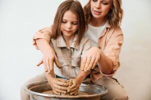 Making, the pot ,out of clay. Mother with little girl doing pottery at home photo
