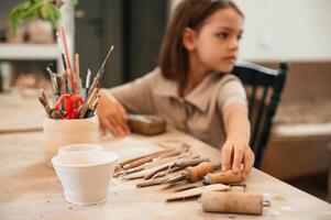 Different tools ,on the, table. Little girl is learning how to do pottery in the workshop photo