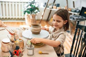 Little, girl is learning ,how ,to do pottery in the workshop photo