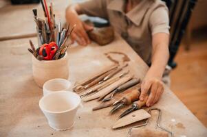 Different ,tools ,on the table. Little girl is learning how to do pottery in the workshop photo