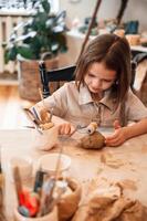 Working with clay. Little,, girl is learning how to do pottery in the workshop photo