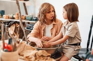 Clay modeling. Mother with, little girl doing pottery at home photo