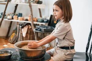 Little, girl is learning how to do pottery in the workshop photo