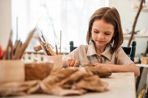 Working with clay. Little, girl is learning how to do pottery in the workshop photo