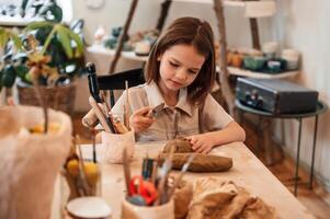 Working, with ,clay. Little girl is learning how to do pottery in the workshop photo