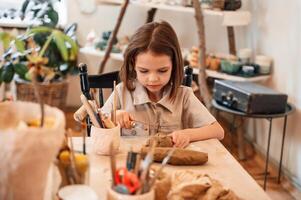 Working ,with ,clay. Little girl is learning how to do pottery in the workshop photo