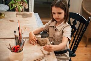 Little ,girl is learning how to do pottery in the workshop photo