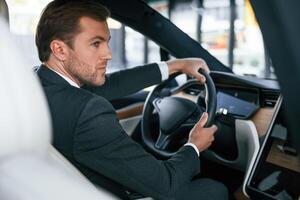 Rear, view. Businessman, in suit is driving his electric car photo