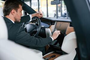 Rear view. ..Businessman in suit is driving his electric car photo