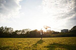 Beautiful,, sunlight. Happy little girl is playing with kite on the summer field photo