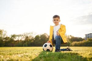 On the, ground. Boy is on the summer field with soccer ball photo