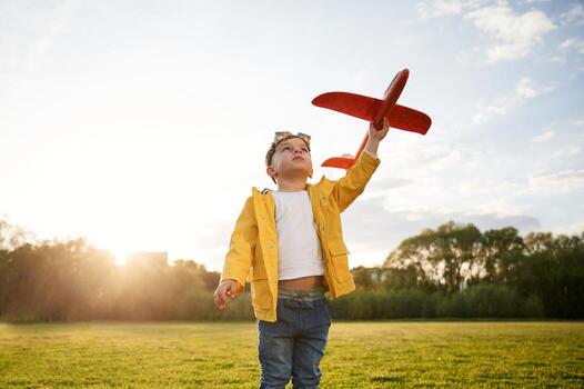 Sunlight ,is above the trees. Littl,e boy is playing with toy plane on the summer field photo