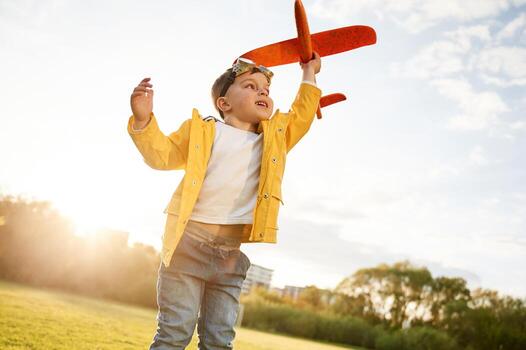 Sunlight is above the trees. Little ,boy is playing with toy plane on the summer field photo