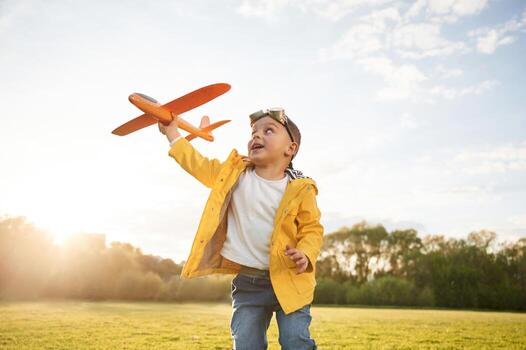 Sunlight is above the trees., Little boy is playing with toy plane on the summer field photo
