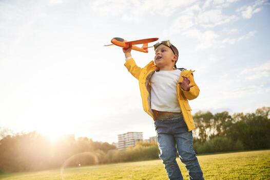 Sunligh,t is above the trees, Little boy is playing with toy plane on the summer field photo