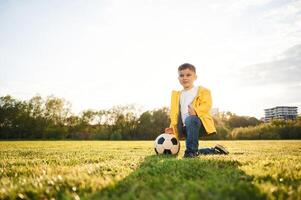 On the ground., Boy is on the summer field with soccer ball photo