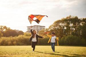 Two kids, are ,playing with kite on the summer field photo