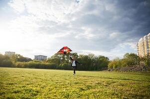 Happy little girl is playing ,with kite on the summer field photo