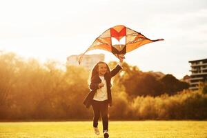 Beautiful ,sunlight.. Happy little girl is playing with kite on the summer field photo