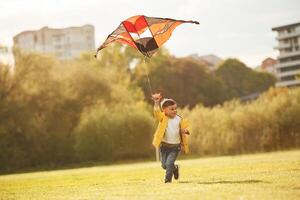 Running with ,kite. Little ,boy is playing on the field at summer time photo