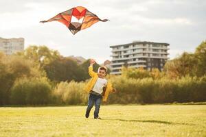 Running ,with ,kite. Little ,boy is playing on the field at summer time photo