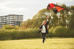 Photo ,in motion. Happy little girl is playing with kite on the summer field