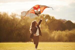Beautiful ,sunlight. Happy little girl is playing with kite on the summer field photo