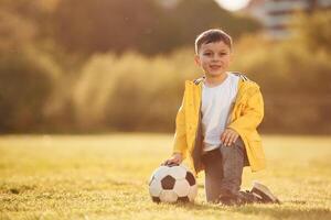 On, the ground. Boy is on the summer field with soccer ball photo