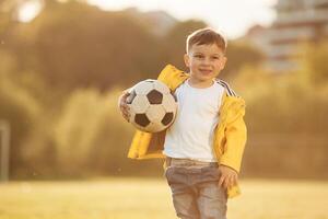 Boy is, on the summer field with soccer ball photo