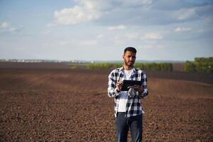 Digital tablet, in hands., On cultivated agricultural field. Handsome Indian man photo