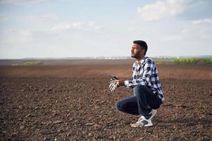 Digital tablet in ,,hands. On cultivated agricultural field. Handsome Indian man photo