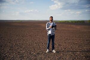 Digital tablet in hands. On cultivated agricultural field. Handsome Indian man photo