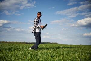 Standing,, and holding notepad. Handsome Indian man is on the agricultural field photo