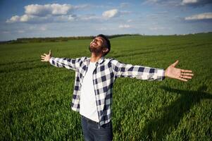 Enjoying ,,freedom, smiling, hands on the sides. Handsome Indian man is on the agricultural field photo