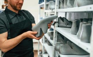 Man is holding shoe in the hands. Conception of industry photo