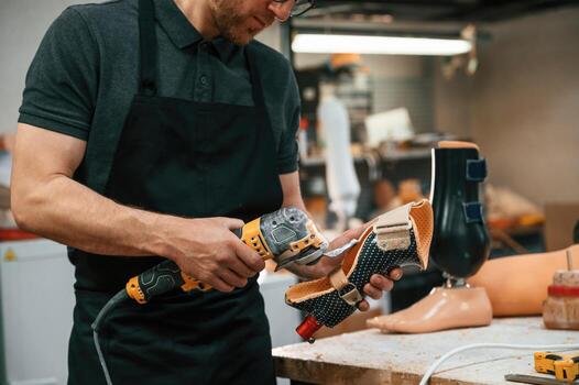 Cuts the ,material ,with drill. Technician working with prosthesis in modern laboratory photo