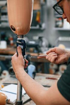 Assembles ,the prosthesis, using tool. Technician working in modern laboratory photo