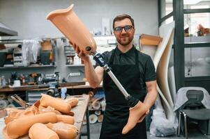 With prosthesis, in hands. Technician, working with prosthesis in modern laboratory photo